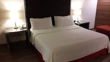 Une chambre d’hôtel avec un lit, deux tables de chevet, une petite table, une chaise rouge et un mur d’accent en bois.