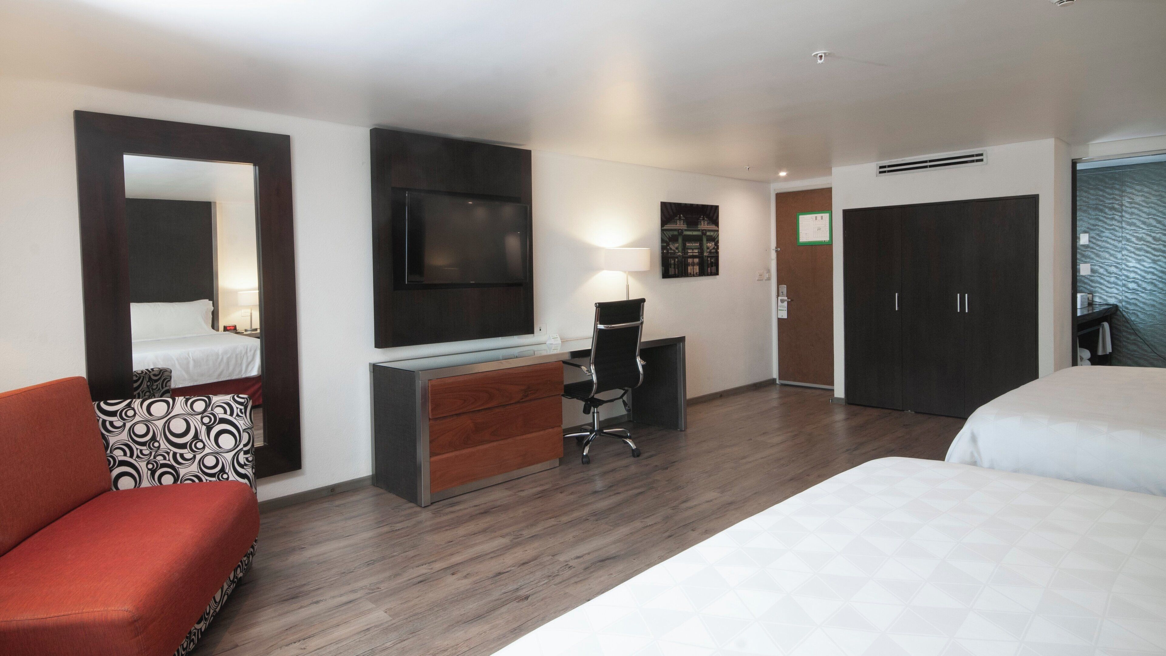 A hotel room with a bed, a desk, a chair, a TV, a wardrobe, and a bathroom.