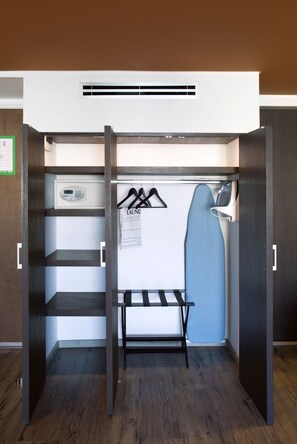 Een compacte kamer met een geïntegreerd strijkstation, een droogrek en een kledingrek.