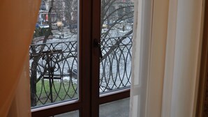A view through a window with a metal fence and buildings in the background. - Wien Hotel (Lviv)