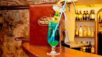 A bar area with a cocktail in a glass, a menu, and a selection of bottles in the background.
