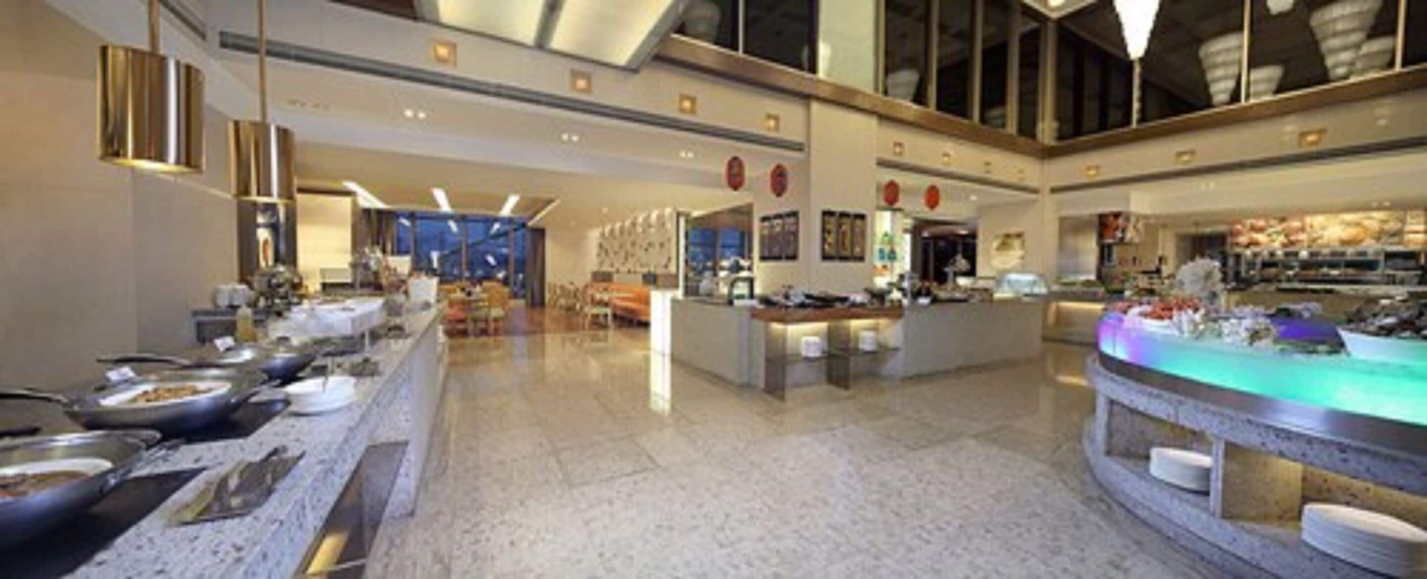 A spacious hotel lobby with a long buffet table, a reception desk, and a large window providing a view of the interior.