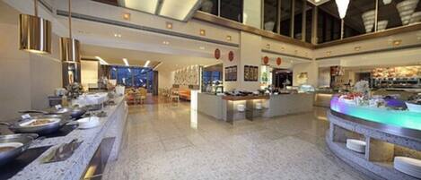 A spacious hotel lobby with a long buffet table, a reception desk, and a large window providing a view of the interior.