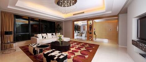 A modern living room with a large TV, a white sofa, and a patterned rug.
