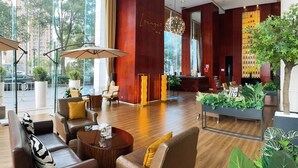 A spacious lobby with leather sofas, a reception desk, and large windows offering a view of the city. - The Eton Hotel (Shanghai)