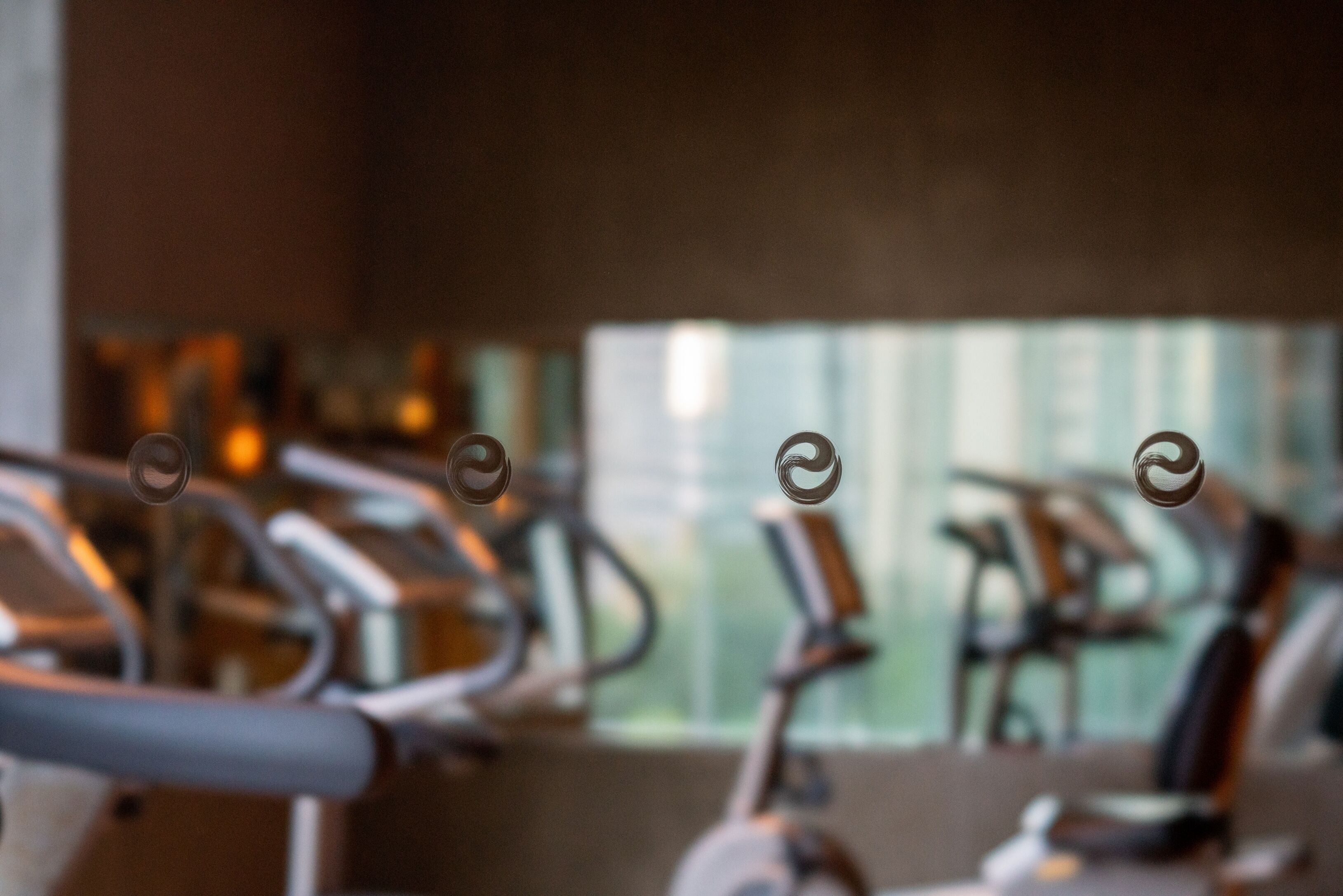Uskarpt billede af træningsudstyr i et fitnesscenter med et vindue i baggrunden.