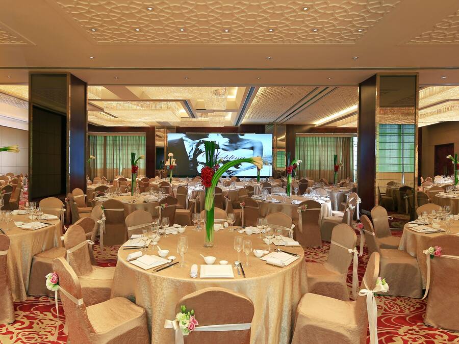 Un salón de banquetes con mesas redondas, sillas y centros de mesa florales.