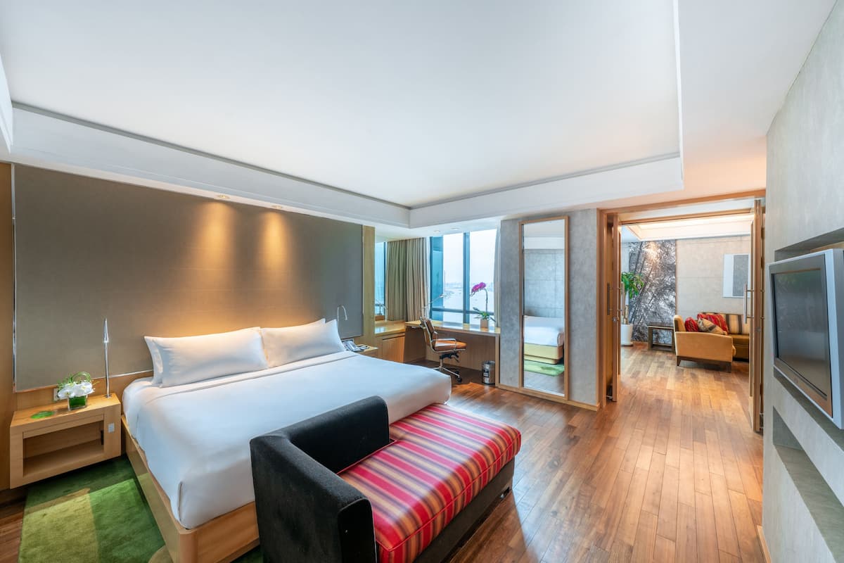 A modern hotel room with a large bed, a desk, a chair, and a TV.