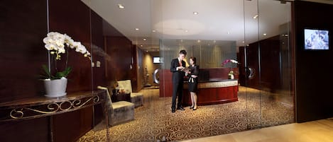 A reception area with a reception desk, a potted plant, and a seating area with chairs.