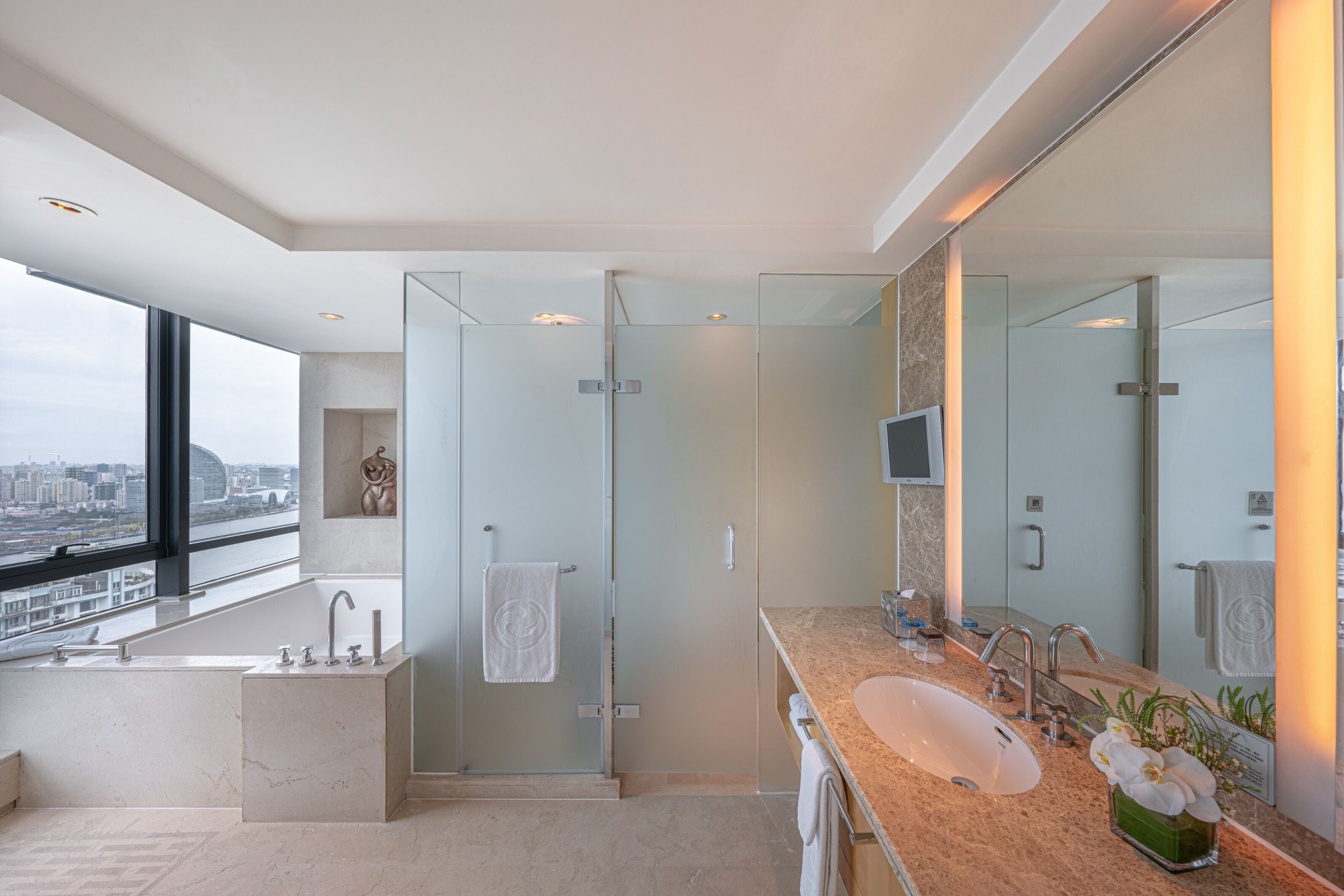 A modern bathroom with a large bathtub, a walk-in shower, a vanity with a sink, and a large mirror.