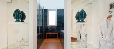 Un baño moderno con ducha de vidrio, un banco y jarrones decorativos.