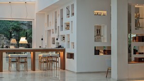 A modern interior with a bar area, seating, and built-in shelves displaying various items. - Hotel Conca Park (Sorrento)