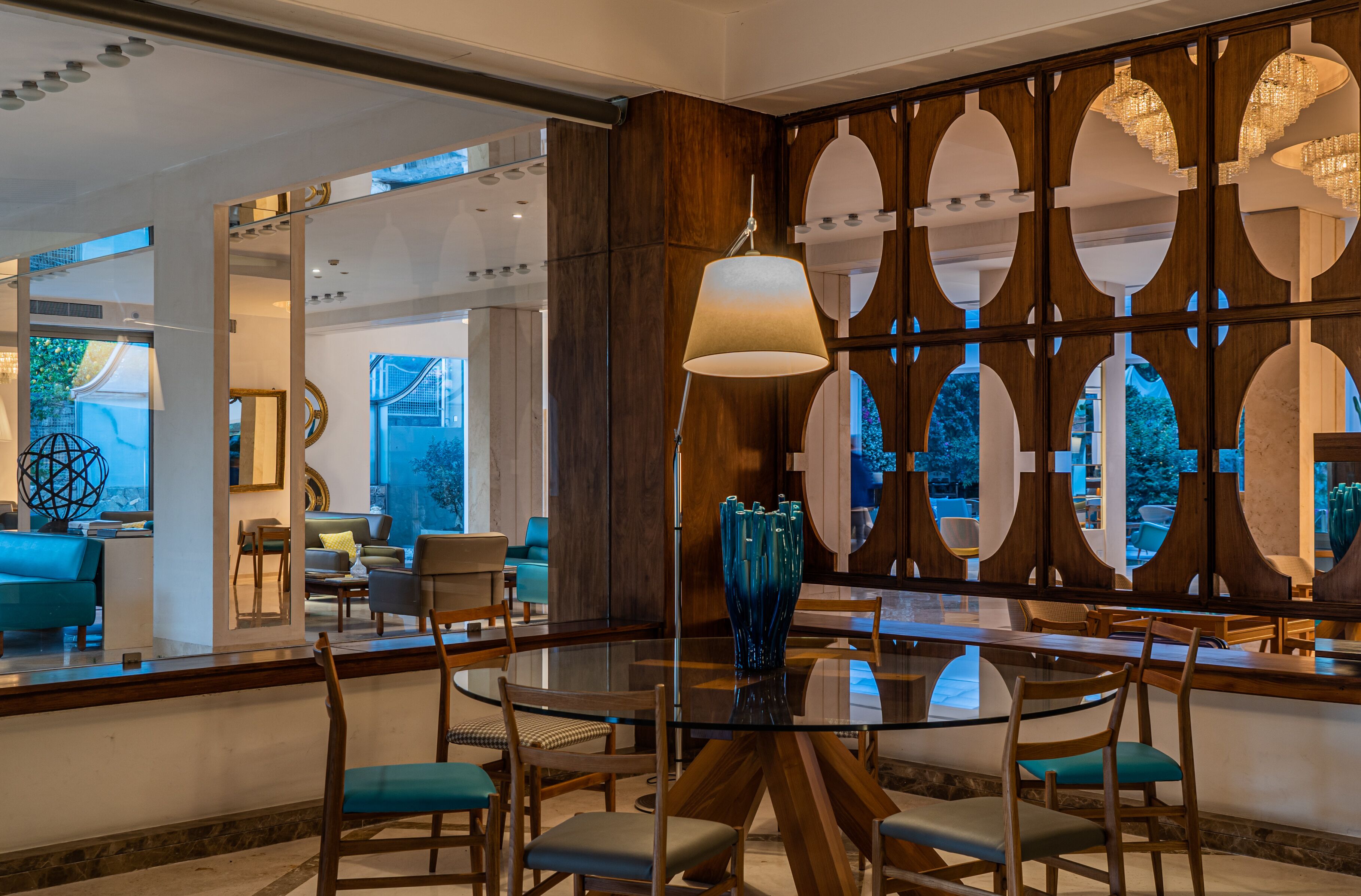 Un comedor moderno con una mesa de vidrio, sillas de madera y una pared decorativa con círculos.