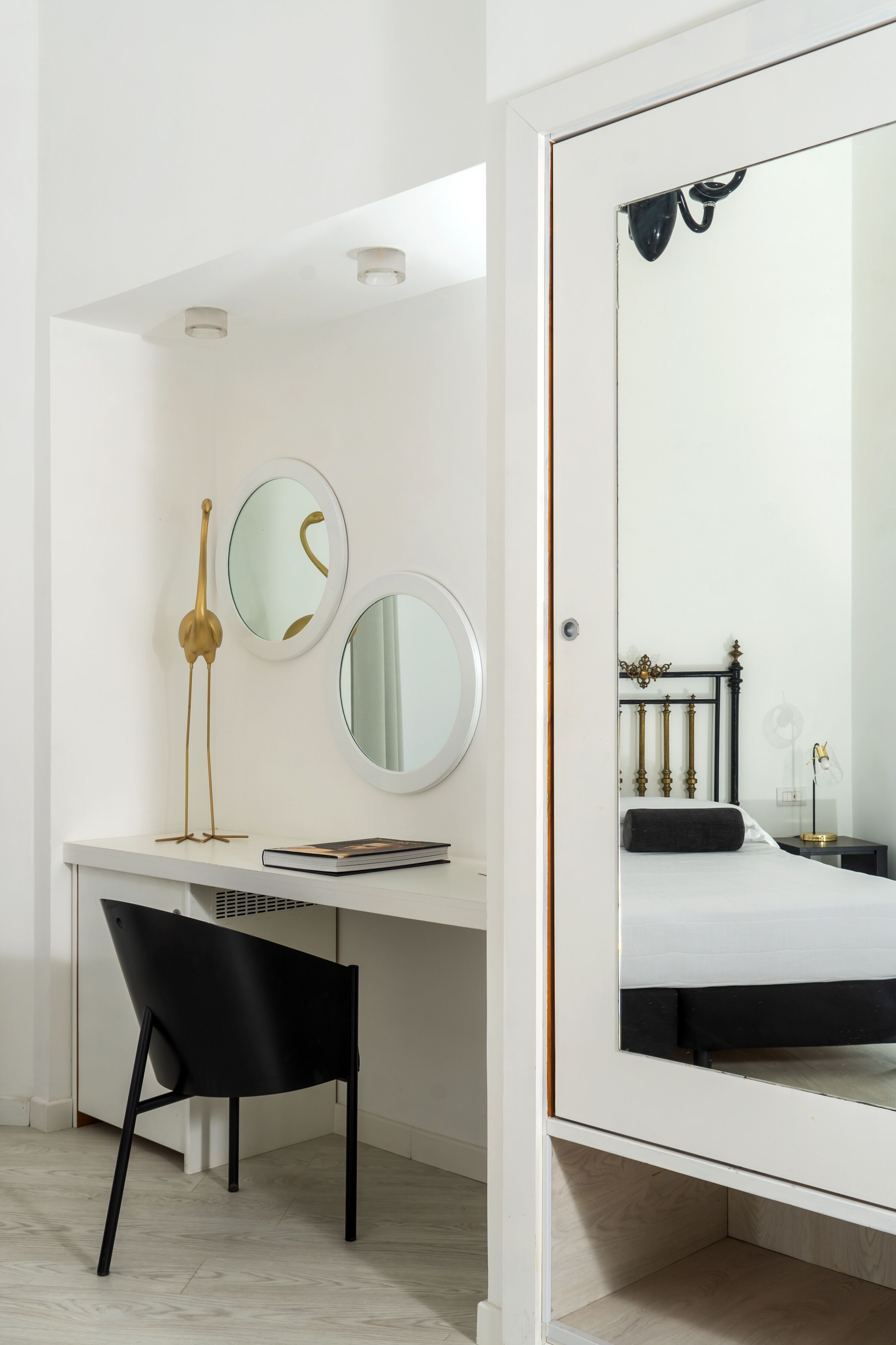 Une chambre moderne avec un lit blanc, un grand miroir et un bureau avec une chaise.