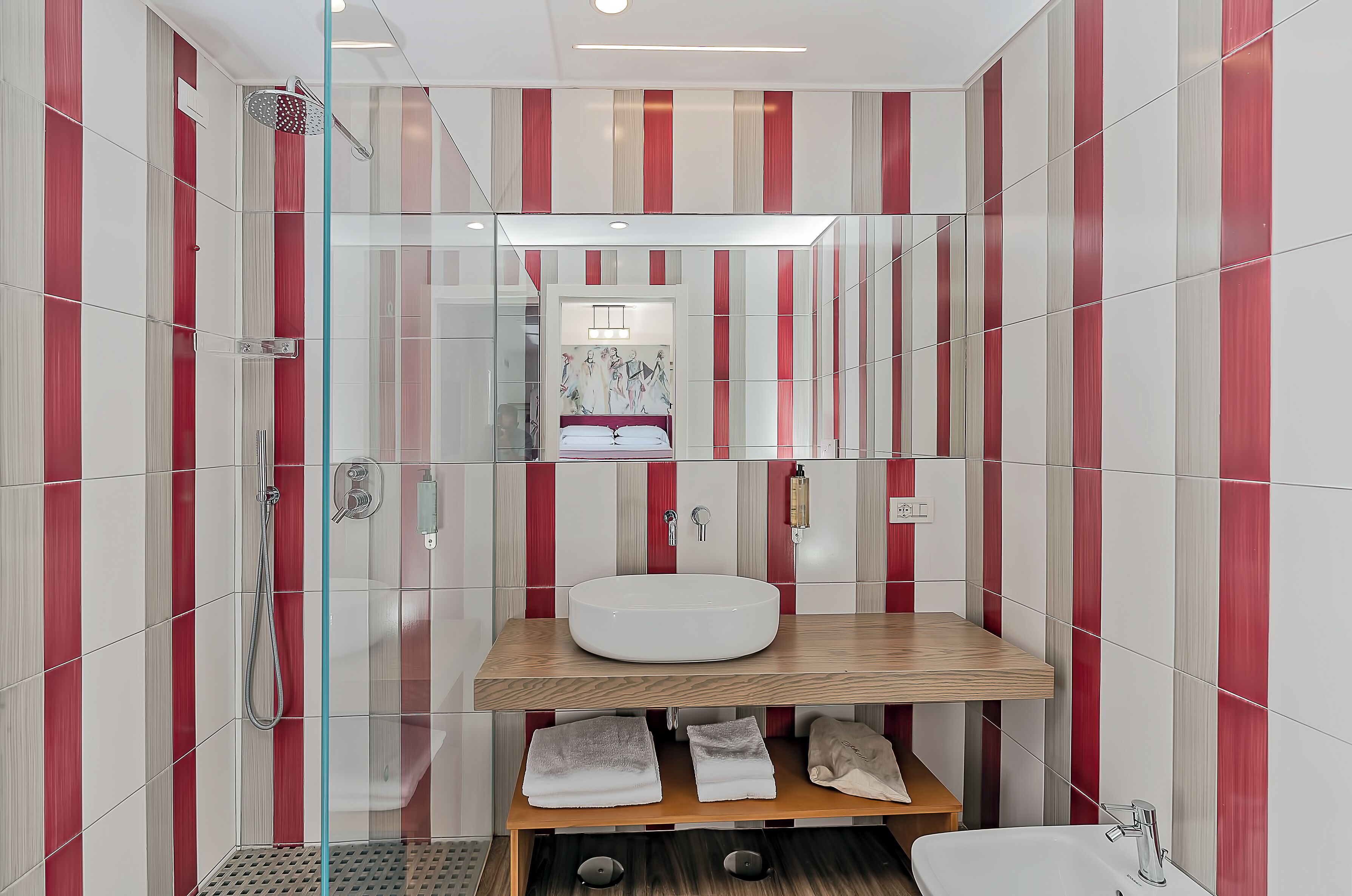 A modern bathroom with a glass shower enclosure, a wooden vanity with a sink, and a mirror above the vanity.