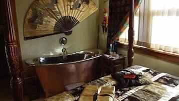 Een slaapkamer met een groot bed, een badkuip en een ventilator.