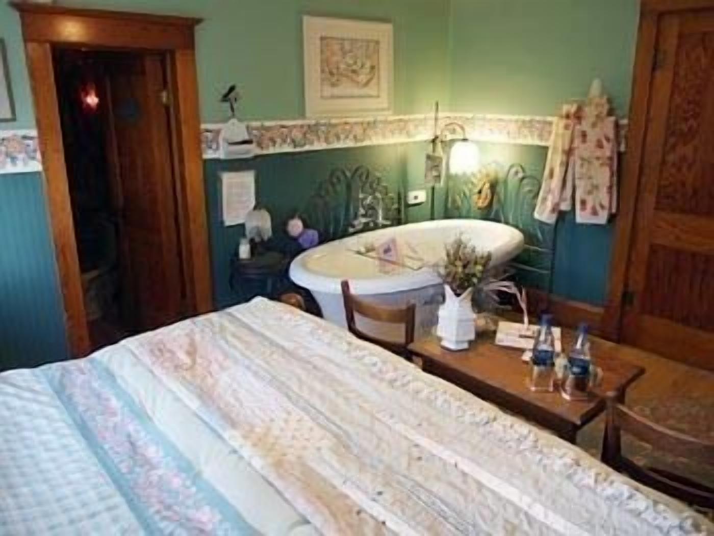 A room with a bed, a small table with toiletries, a sink, and a mirror.