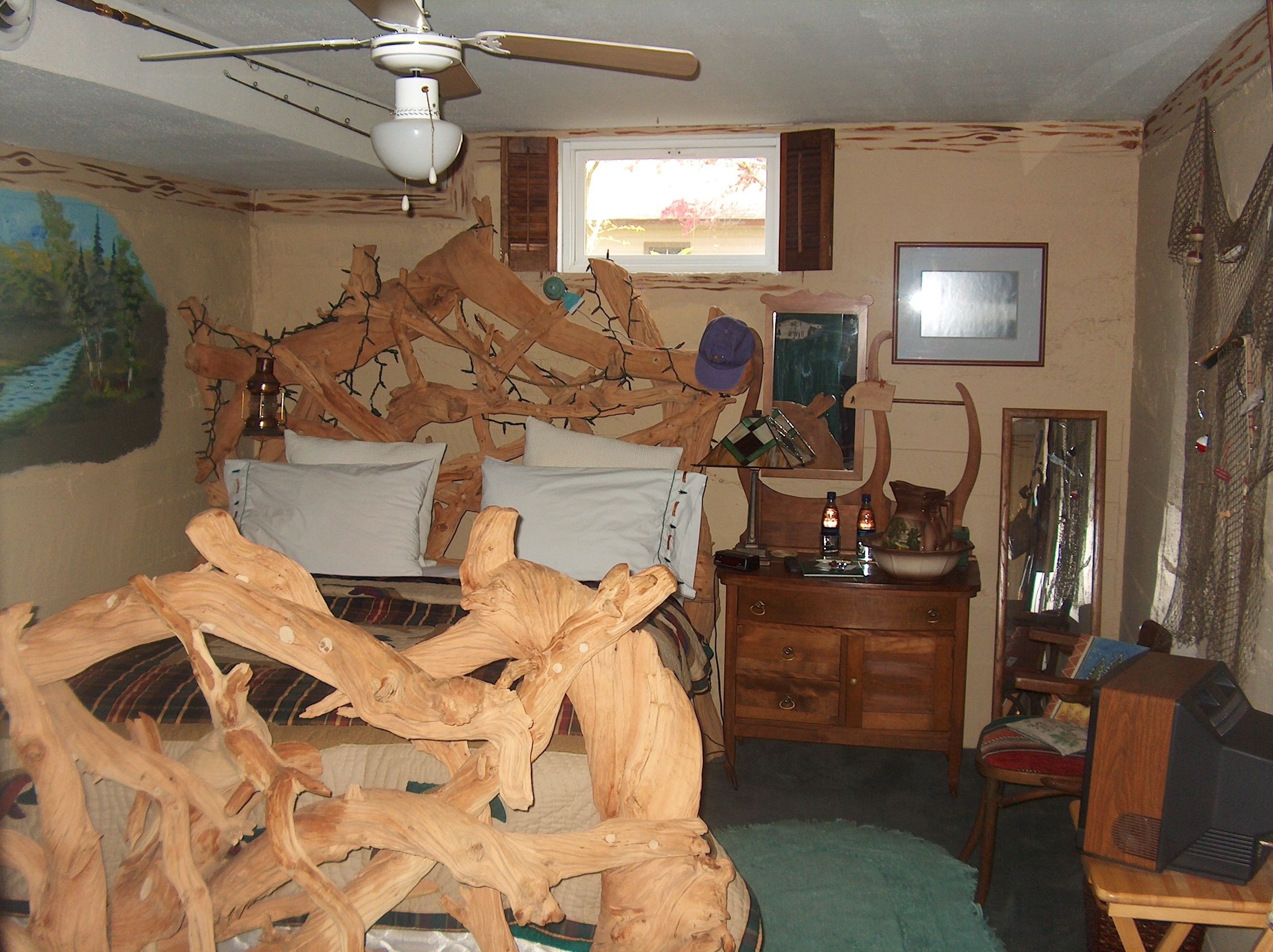 Ein Zimmer mit einem Bett, einem Holzkopfende, einem Deckenventilator, einem Schminktisch, einem Stuhl und einem Fernseher.