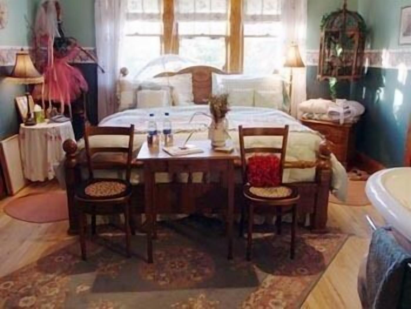Ein gemütliches Schlafzimmer mit einem Bett, zwei Stühlen, einem Tisch und einem Nachttisch.