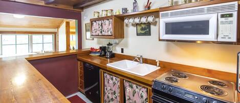A kitchen with wooden cabinets, a stainless steel stove, a microwave, and a sink.