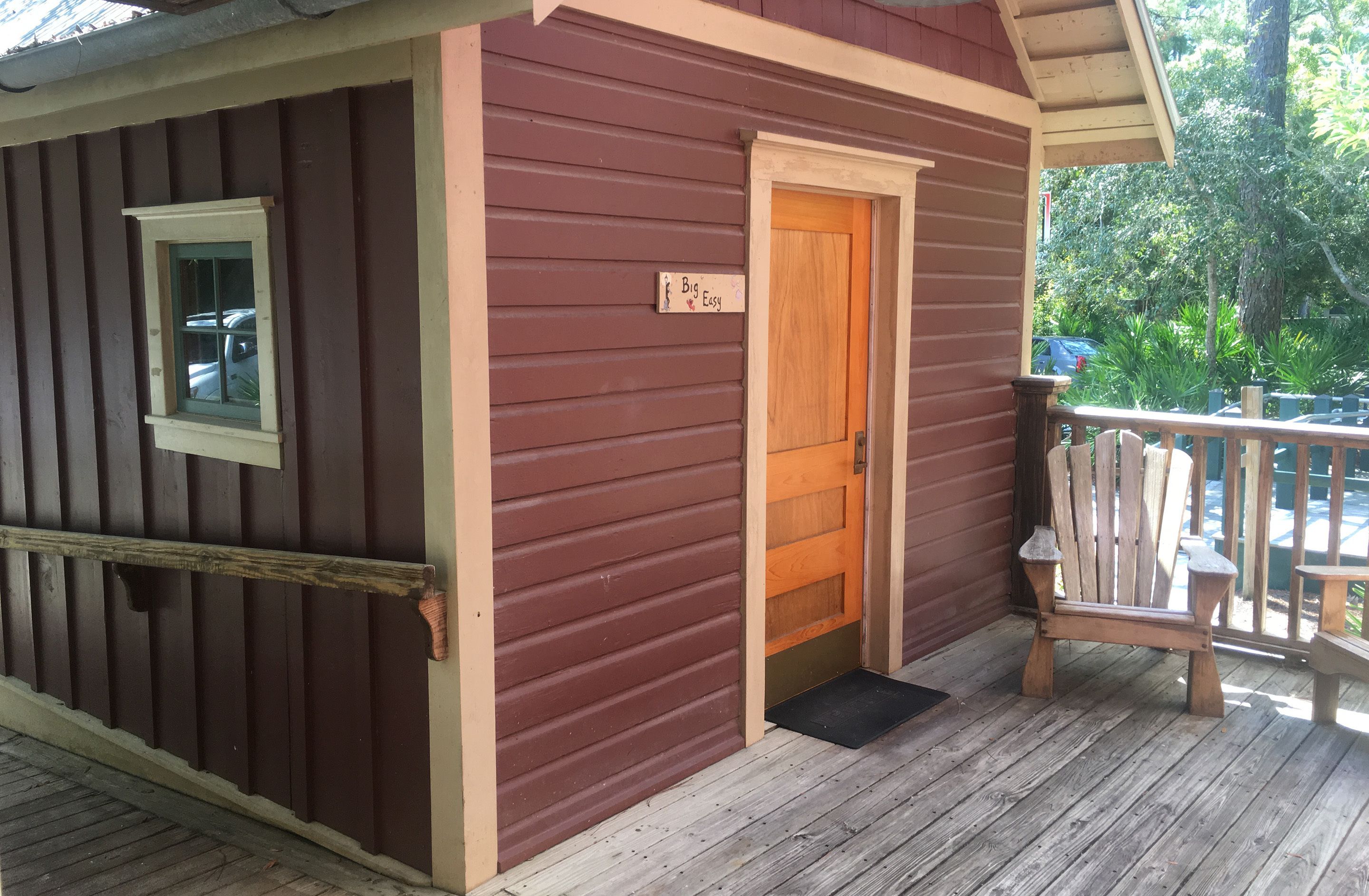 A wooden cabin with a door, a small window, and a porch with a bench.