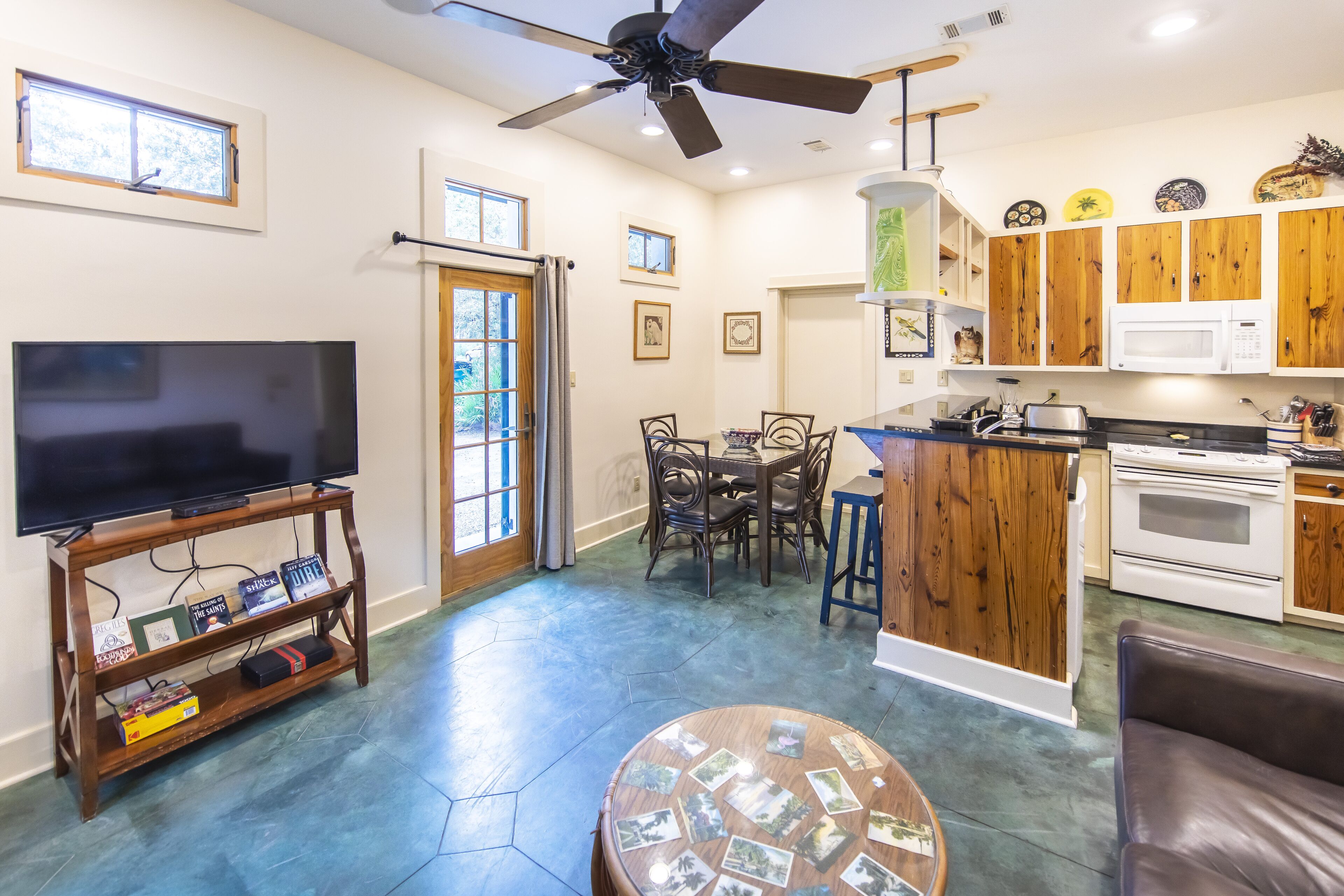A spacious living room with a large TV, wooden furniture, and a dining area.