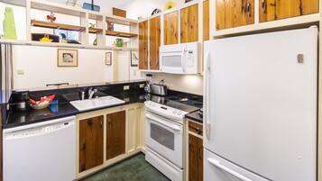 A kitchen with wooden cabinets, a white refrigerator, a microwave, a stove, and a dishwasher.