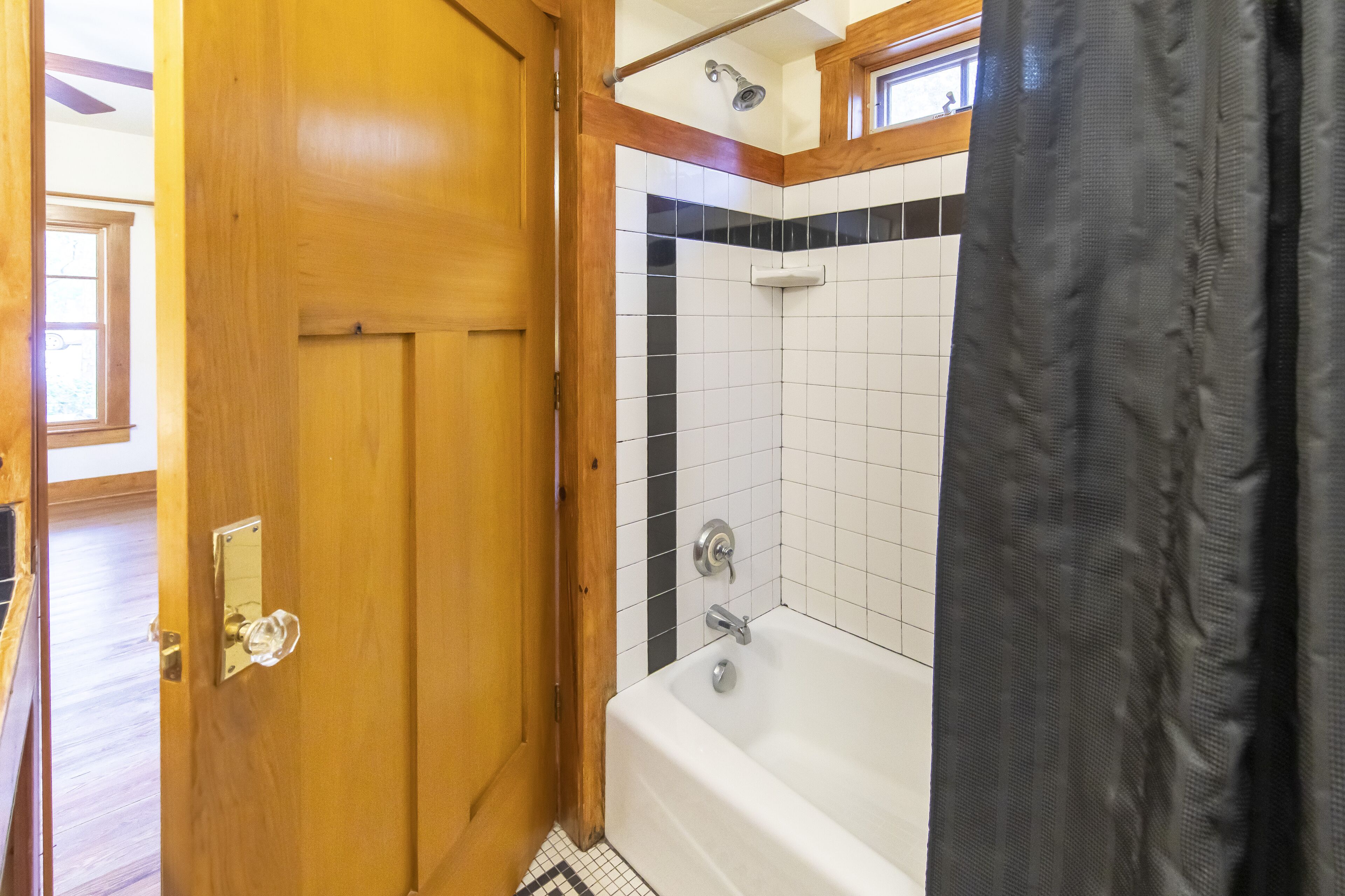Une salle de bain avec une porte en bois, une baignoire et un espace douche.