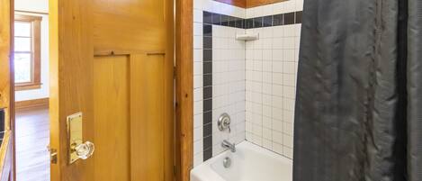 Une salle de bain avec une porte en bois, une baignoire et un espace douche.