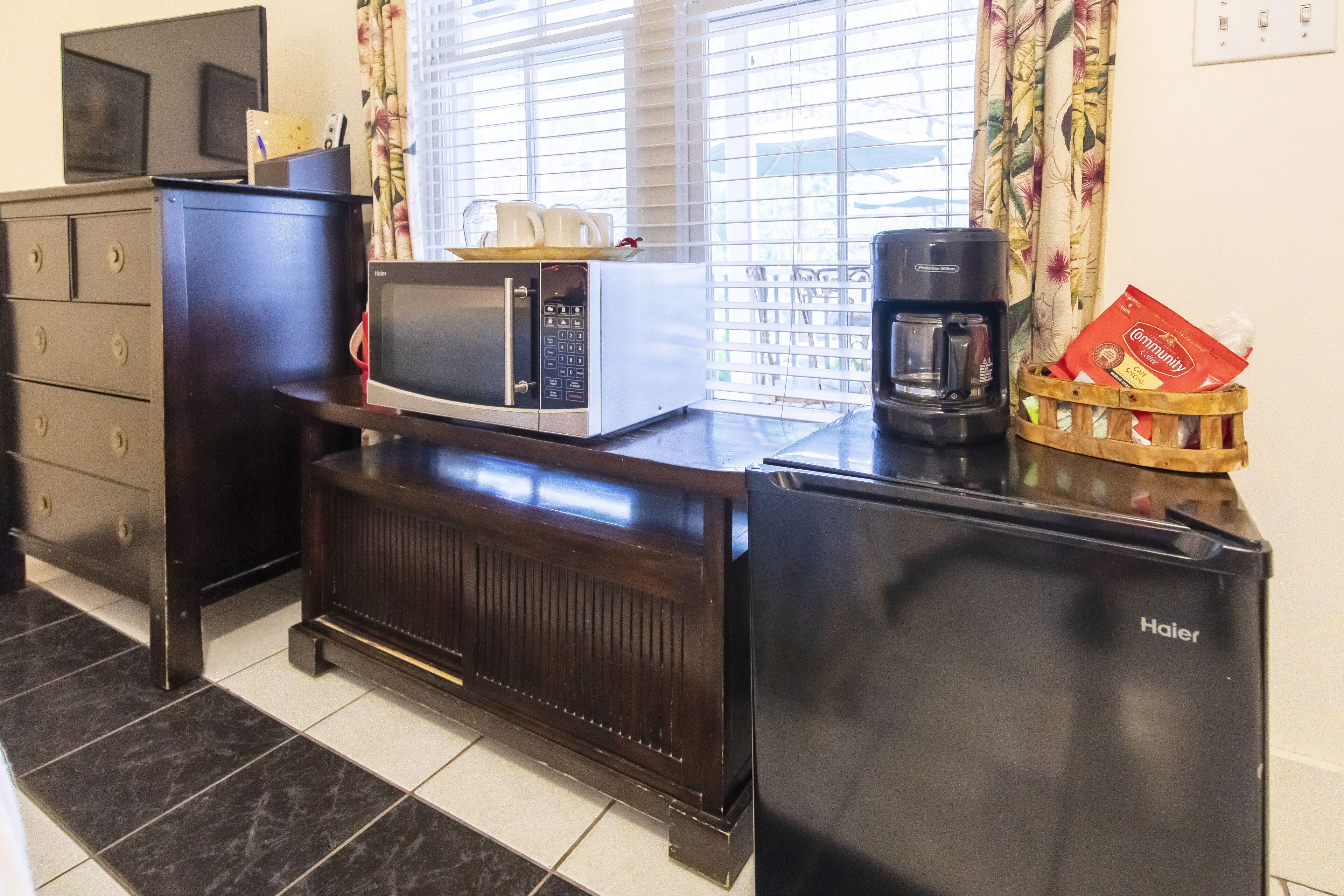 A compact kitchenette with a microwave, coffee maker, and a refrigerator.