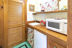 A compact kitchen with a wooden countertop, a white microwave, a small sink, and a refrigerator.