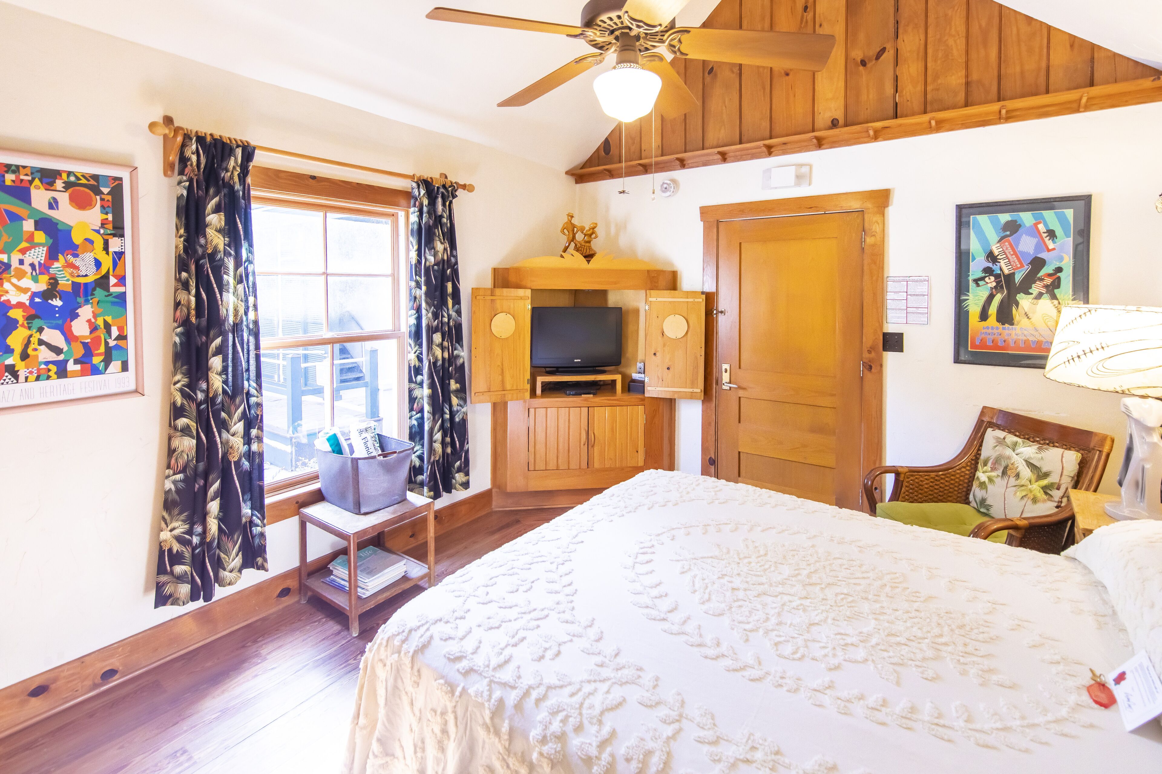 A room with a bed, a television, wooden furniture, and artwork on the walls.