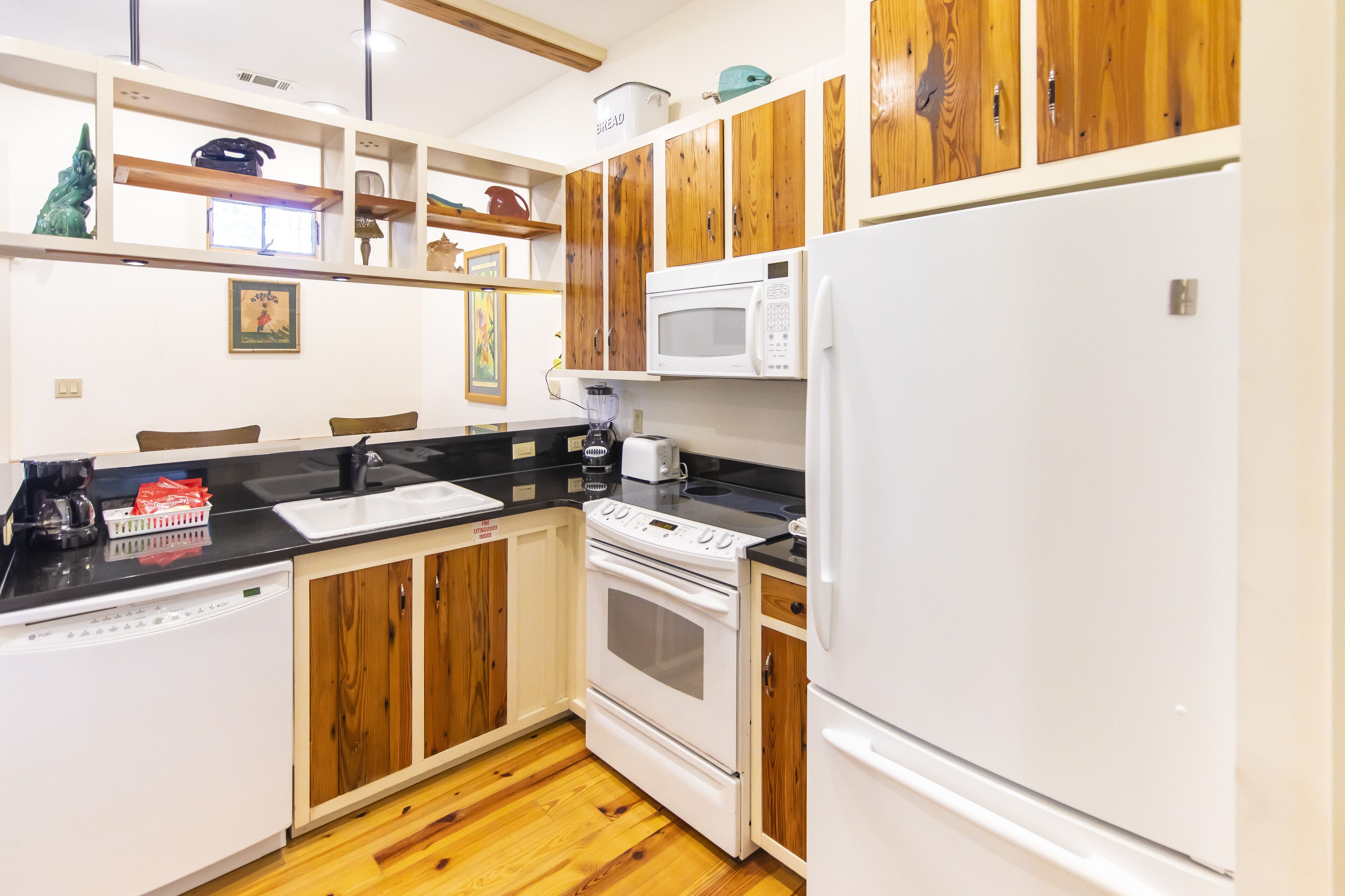 A kitchen with wooden cabinets, a white refrigerator, a microwave, a stove, and a dishwasher.