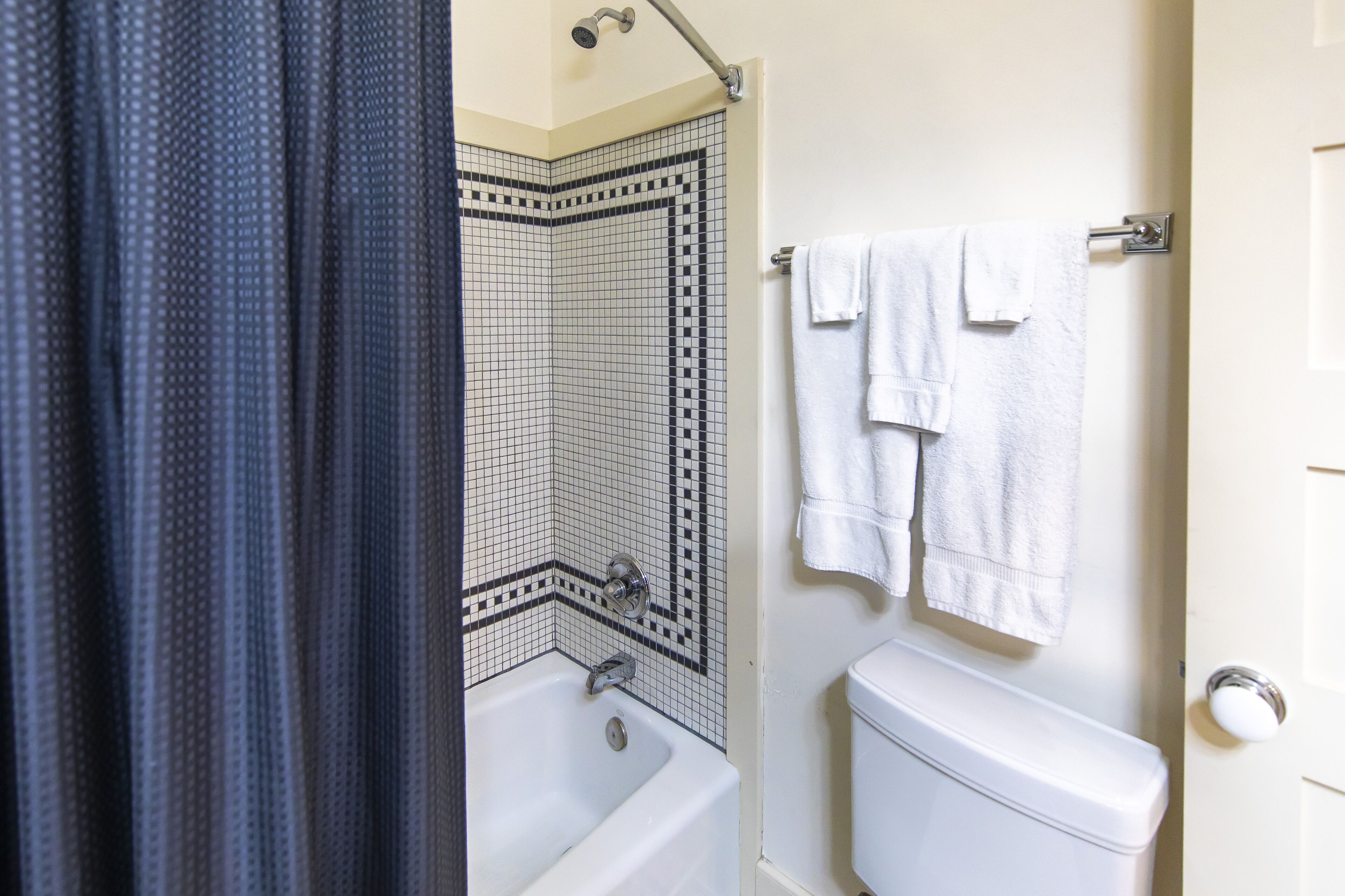 A bathroom with a white bathtub, a shower with a corner tile design, and a toilet.