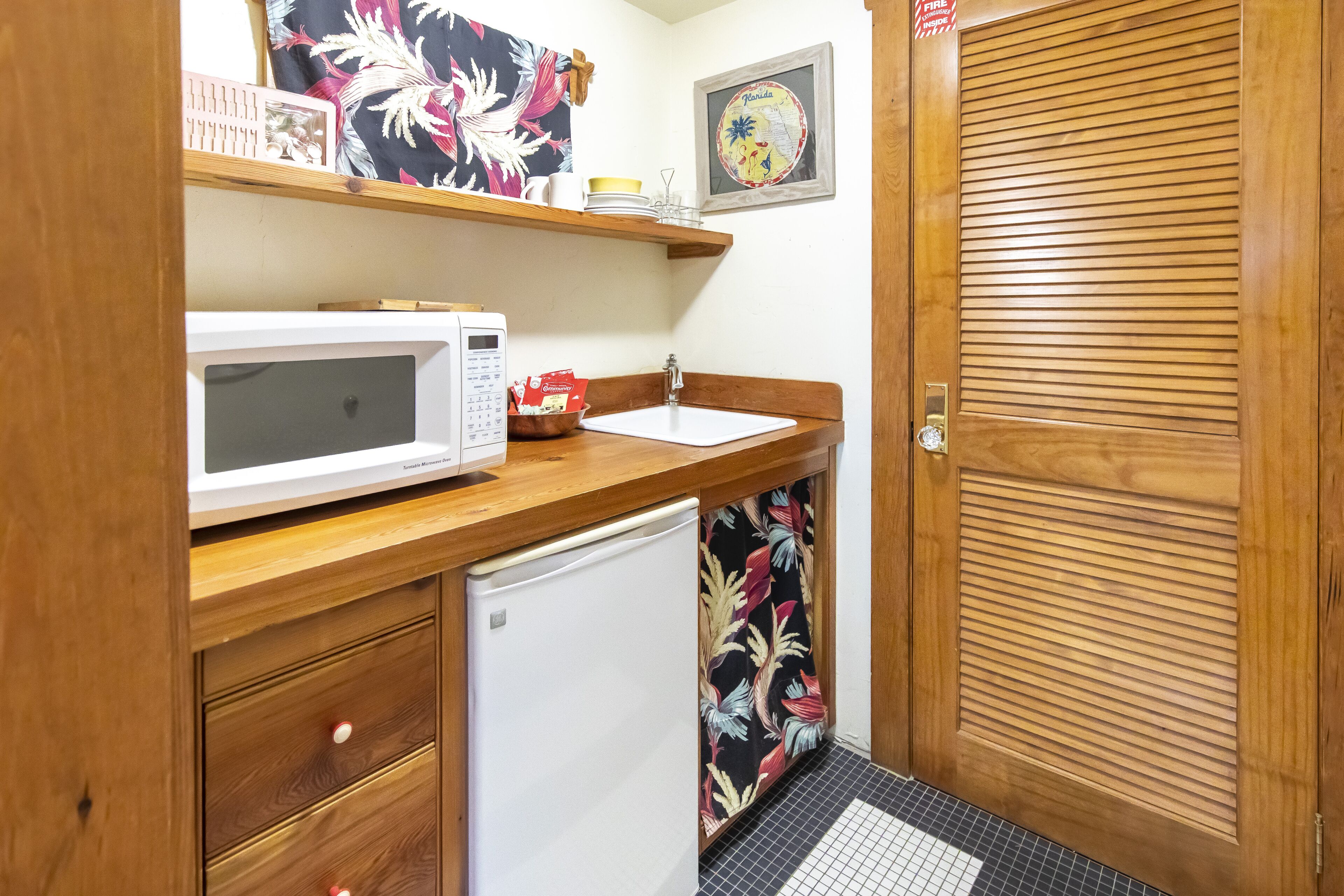 A compact kitchen with a microwave, sink, and refrigerator.