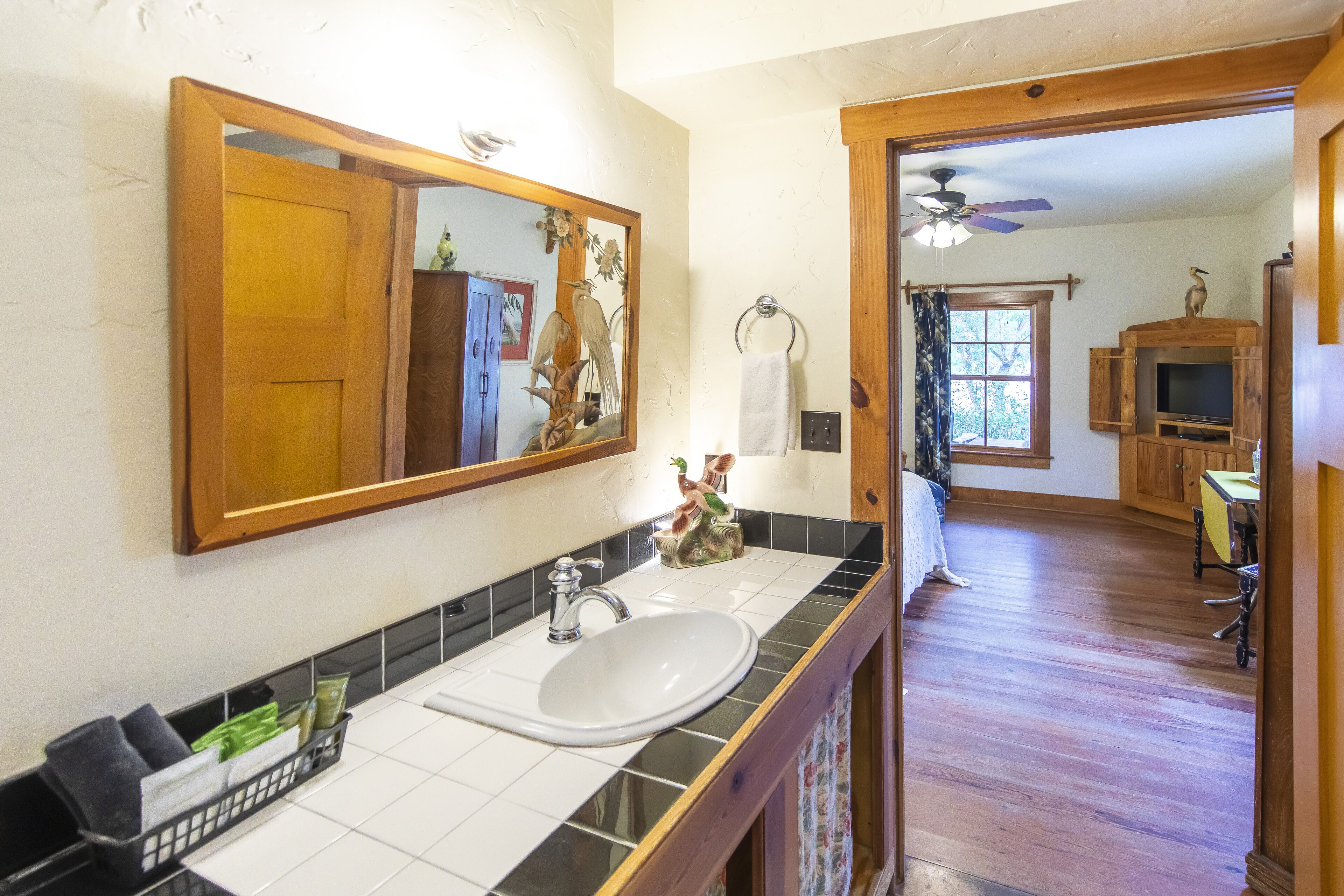 A bathroom with a wooden vanity, a white sink, and a large mirror.