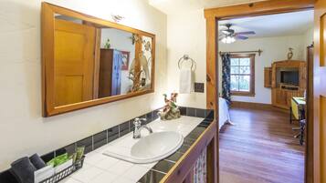 A bathroom with a wooden vanity, a white sink, and a large mirror.