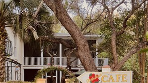 A pathway leading to a building with a sign indicating a cafe. - Hibiscus Coffee & Guesthouse (Santa Rosa Beach)