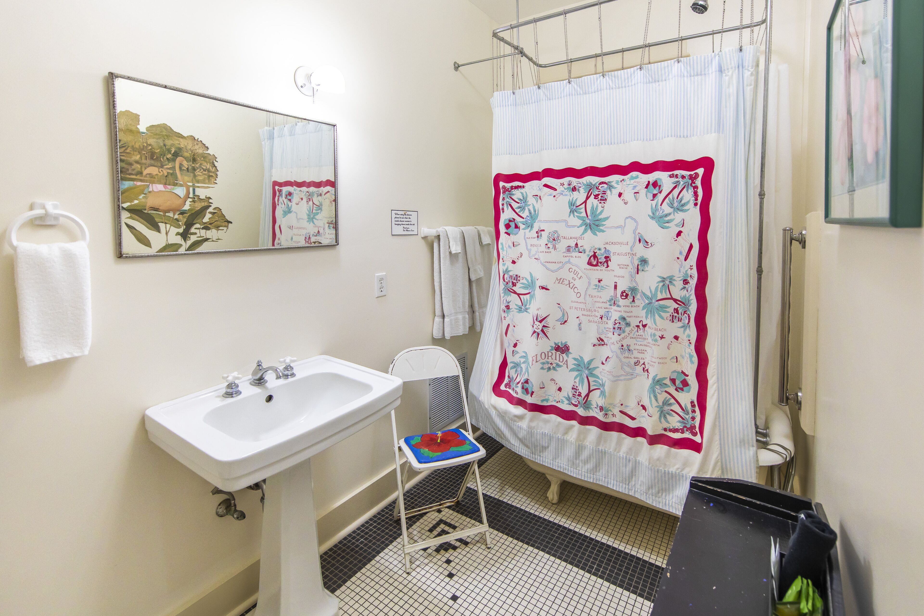 A bathroom with a white sink, a mirror, a shower curtain with a floral pattern, and a tiled floor.