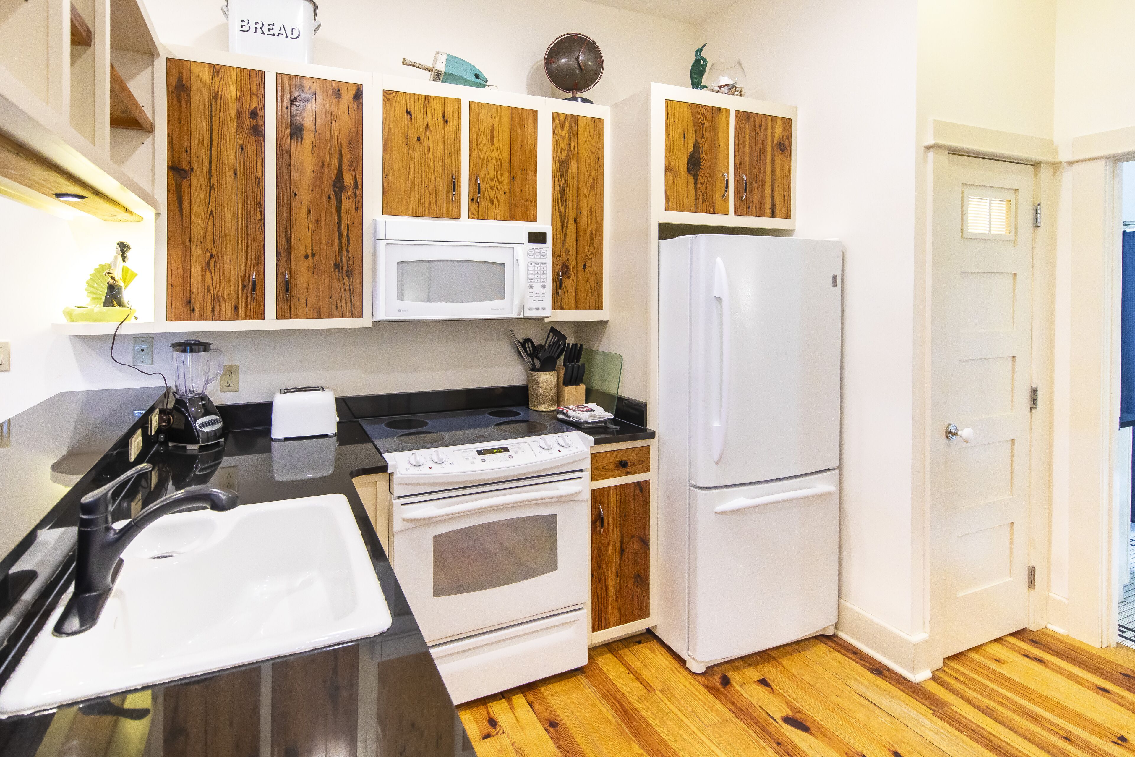 Una cocina con armarios de madera, microondas, estufa, refrigerador y fregadero.