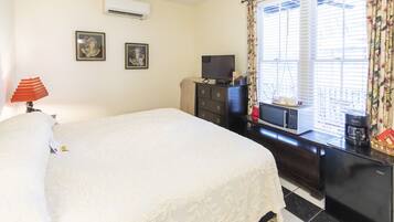 A hotel room with a bed, a dresser, a television, and a window with curtains.