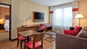 A hotel room with a wooden desk, a television, a sofa, and a bed. - Four Points by Sheraton Moncton (Moncton)