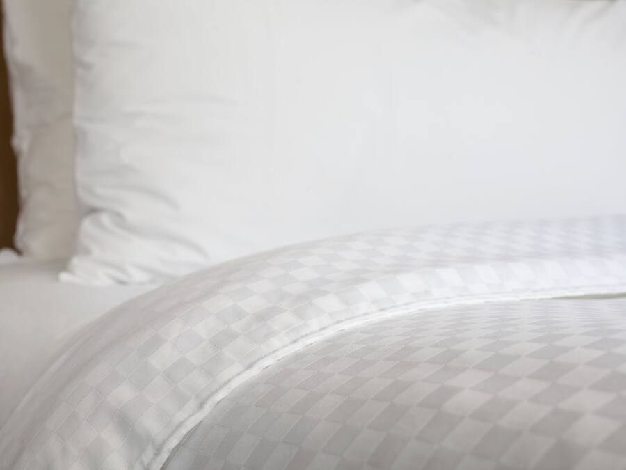 Uma cama com um edredom estampado e almofadas.