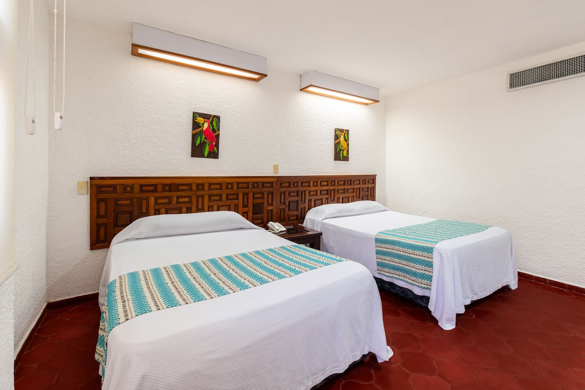 A hotel room with two beds, a wooden headboard, and artwork on the wall.