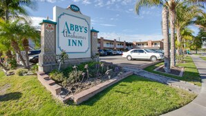 A sign for 'Abbey's Unachievable Inn' with a parking area and palm trees in the foreground. - Abby's Anaheimer Inn (Anaheim)