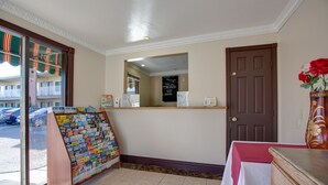 A reception area with a bulletin board, a wooden counter, a door, and a vase with flowers. - Abby's Anaheimer Inn (Anaheim)