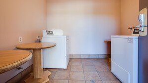 A compact kitchen with a wooden table, a white refrigerator, and a small sink. - Abby's Anaheimer Inn (Anaheim)
