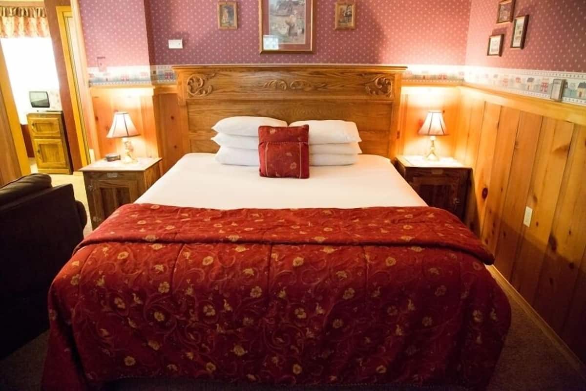 A hotel room with a large bed, wooden headboard, and two bedside tables with lamps.