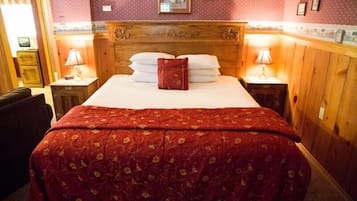 Ett hotellrum med en stor säng, ett träfärgat sänggavel och två sängbord med lampor.