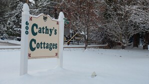 Een bordje voor 'Cathy's Cottages' in een besneeuwde omgeving.